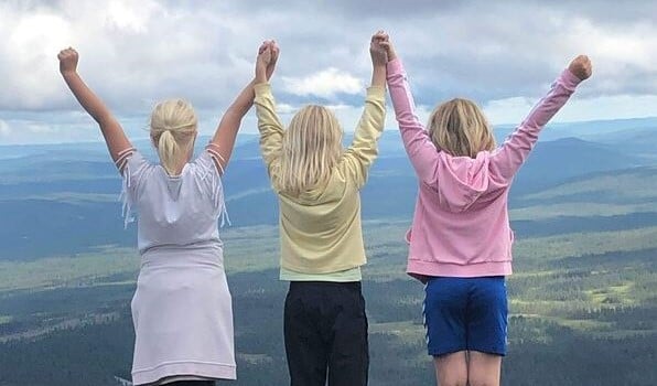 Tre jenter med hendene i været på fjellet